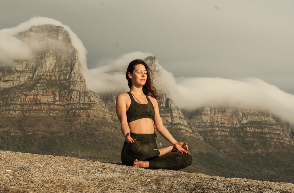 Woman in Black Sports Bra and Black Pants Sitting on Rock. Calming Storm of stress